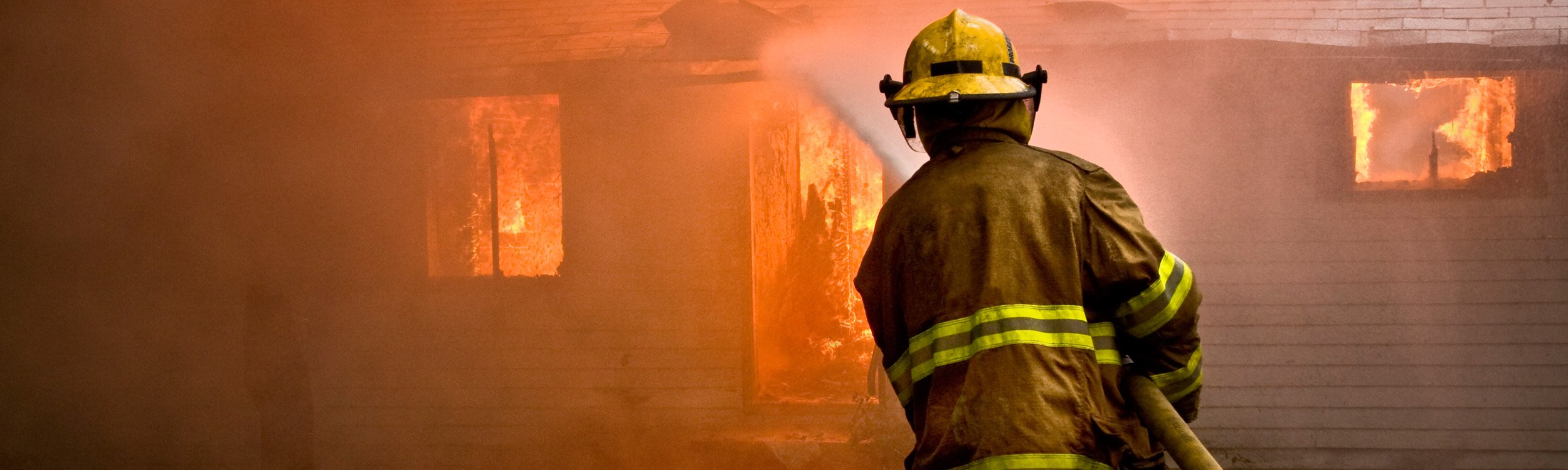 fireman hosing down a burning structure