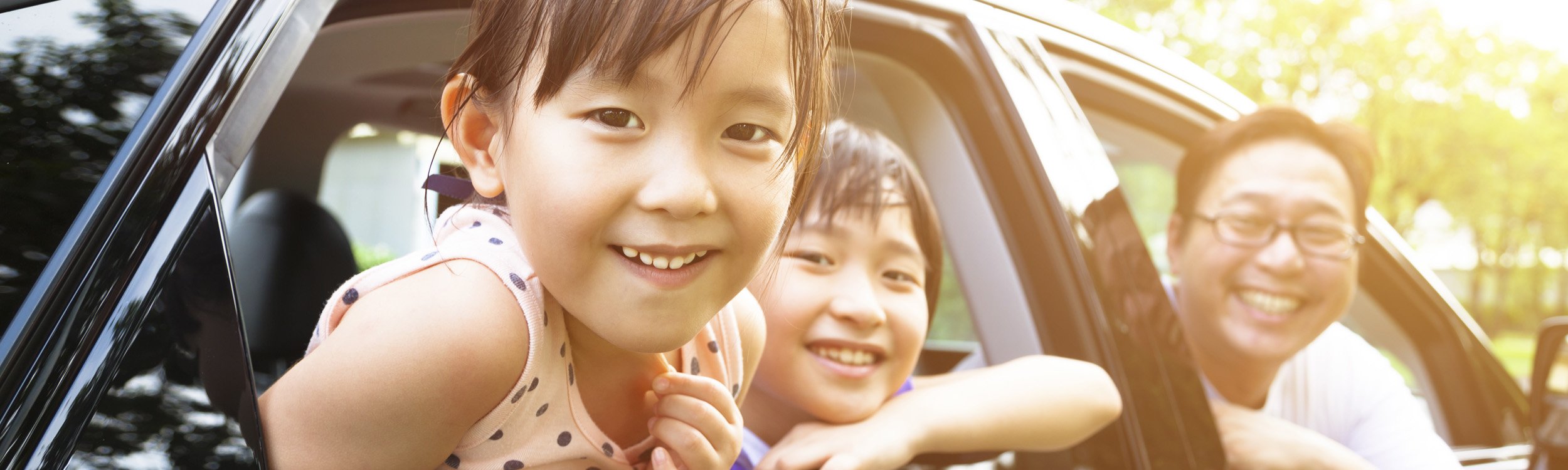 asian family of 3 smiling in a car